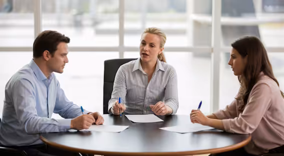 Eine Rechtsanwältin im Mediationsgespräch mit einem Mann und einer Frau an einem runden Tisch
