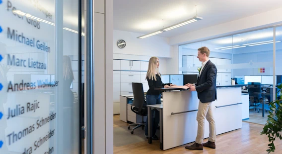 Ein Rechtsanwalt und eine Rechtsanwältin im Gespräch am Thresen der Kanzlei