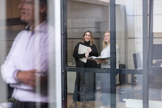 Drei Rechtsanwälte und Rechtsanwältinnen in der Kanzlei, fotografiert durch ein Fenster